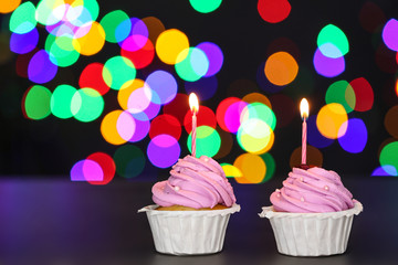 Tasty Birthday cupcakes on table against defocused lights