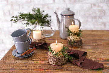 Coffee pot, cups and burning candles on table