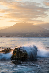 Sunrise in Almoxarife, Horta, Faial island: Spray of splashing waves and the Volcano of Pico Mountain in the background, Azores Islands, Portugal 