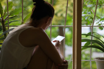 A woman sitting on the windowsill and corresponded on a smartphone.