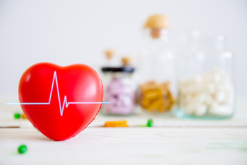 Healthcare and medical concept. Red heart on wooden table with set of medicine bottles and medicine pills background. Copy space for your text.