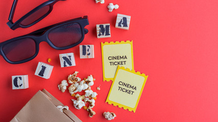 craft bag with popcorn 3d cinema glasses tickets wooden cubes with text on red background creative flatlay