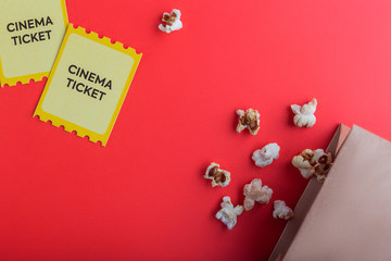 craft bag with popcorn and two yellow cinema tickets on red background flatlay 