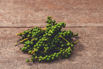 fresh green pepper corns in vine on wooden table