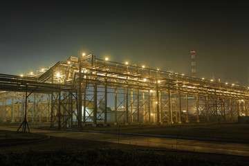 the form of metal pipes of a refinery in the open air at night