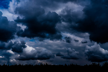 Evening sky background. Dark clouds hanging above horizon. Majestic cloudscape in blue shades. Grey cloudlets bringing rain. Countryside skyline in twilight time