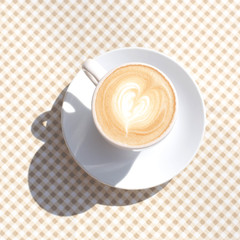 A cup of coffee on the table with a checkered tablecloth.