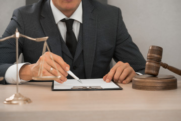 Law and Legal services concept. Male lawyer or judge working with contract papers, Law books and wooden gavel on table in courtroom 