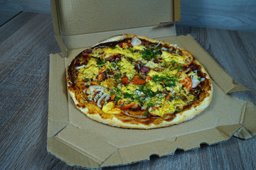  Pizza with mushrooms, sausage cheese and herbs, on the table in a cortoon package.       