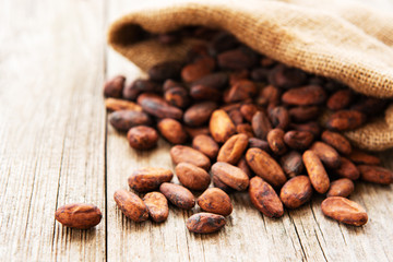 Raw cacao beans in burlap bag on a wooden table