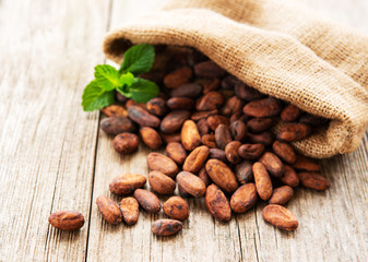 Raw cacao beans in burlap bag on a wooden table