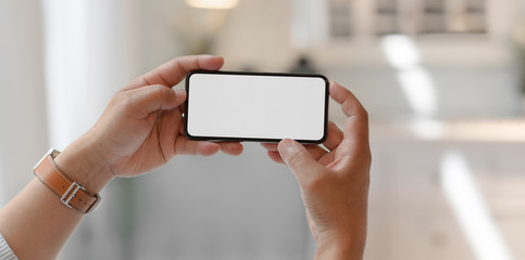 Close-up view of man holding horizontal blank screen smartphone
