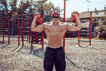 Athletic man working out with a kettlebell at street gym yard. Strength and motivation. Outdoor workout.