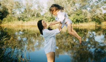 Mother and daughter play and have fun over a river.