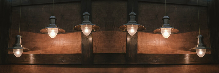 Glowing retro lamps hang on a brown wooden background.
