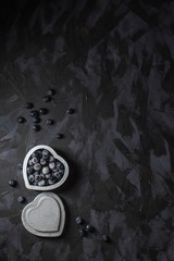 Blueberries with hoarfrost in a silver box heart on a dark background