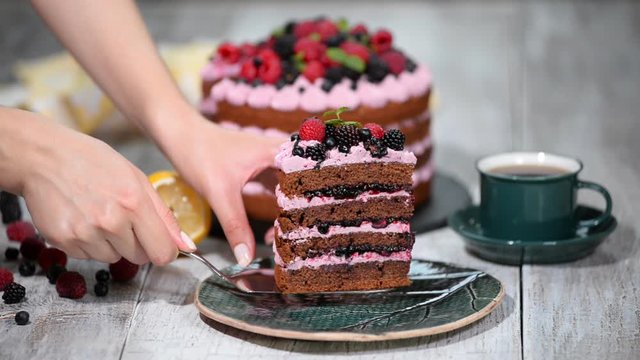Tasty chocolate cake with berries and cup of tea on table close up.