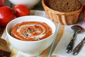 Soup puree with baked tomatoes in a white bowl 