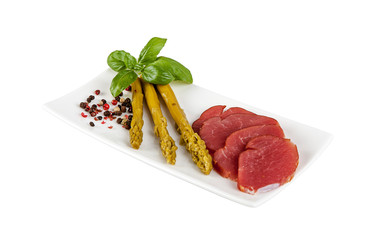 Green asparagus and pork sirloin on a plate on a white background.