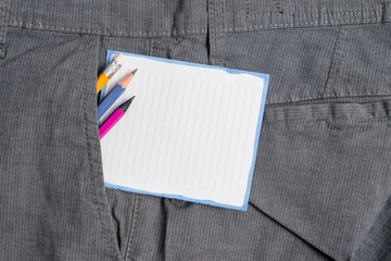 Writing equipment and white note paper inside pocket of man work trousers