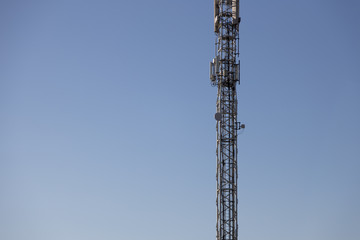 high telecommunication antenna with blue sky background