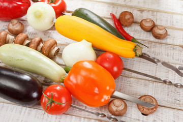 Red pepper, eggplant, zucchini, onions, mushrooms, tomatoes on a wooden table.