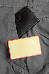 Small little wallet inside man trousers front pocket near notation paper