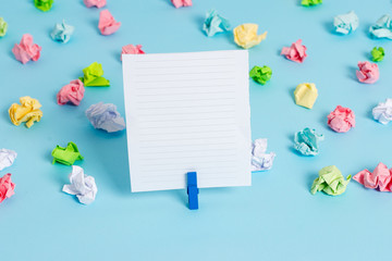 Colored crumpled papers empty reminder blue floor background clothespin