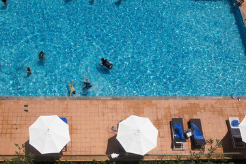 Looking at the blue water of the pool and sunbeds and parasols from above
