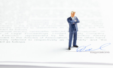 Businessman in a suit and tie ponders a signed contract. Signature on the contract.