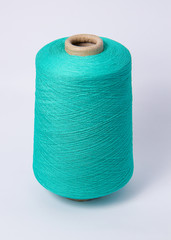 Green bobbin of yarn on a white background.Textile reel on isolated white background.