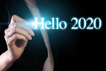 Hand holding a pen and writing hello 2020