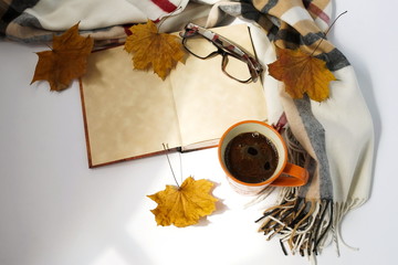 cozy autumn composition. cup of coffee, a warm scarf, glasses, a book  mock up and autumn leaves...
