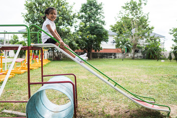 Healthy little kids are playing in the backyard, happy with the swings, rocking horses, slide carriages.