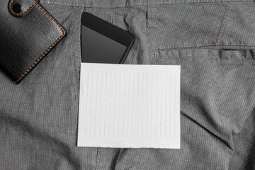 Smartphone device inside trousers front pocket with wallet and note paper