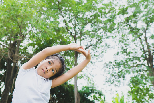 Little Asian Child Girl Doing Yoga In The Public Park.