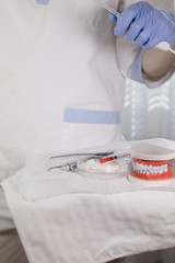 Sterile cotton napkins, human jaw model and stomatological tools on a table. Closeup