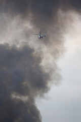Helicopter of State Emergency Service is flying in the cloud of black smoke