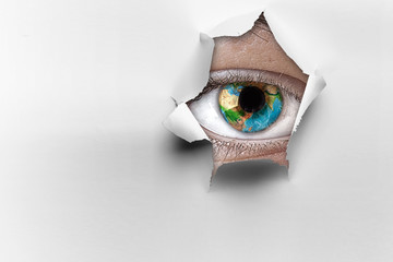 Eye in a hole of torn paper