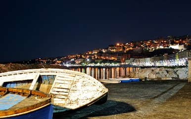 napoli notturna con barche e riflessi della città sul mare