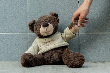 human hand grab the dirty teddy bear from the ground outdoors, lost concept