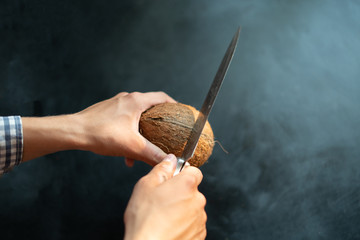 person with big knife try to open and break a coconut