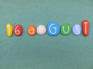 16 August, calendar date composed with multi colored stones over green sand
