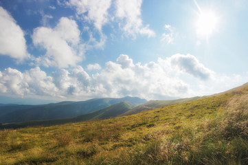 Mountain road with a beautiful cloudy sky on background. Mountain landscape panorama. Noises and large grain - stylization under the film. Soft focus