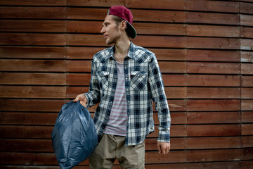 young man taking a trash bag with garbage away