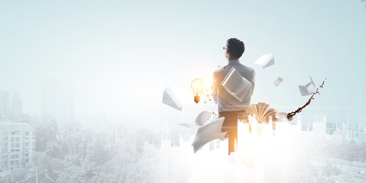 Back view of standing white businessman looking ahead with office objects on cityscape background