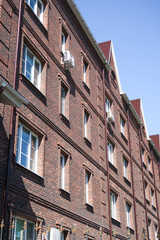 Multi-storey red brick residential building against the blue sky. Summer nature.