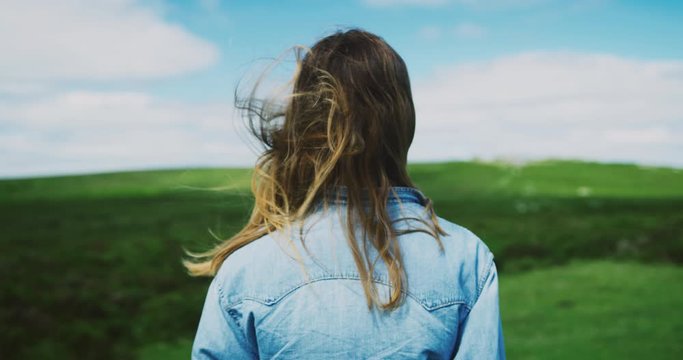 Young woman standing in nature with her hair blowing