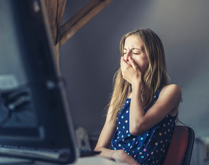 erschöpftes Mädchen sitzt am Computer