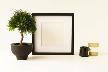 Black frame mock up poster, bonsai tree and candles sushi set on the white desk. Home decor close up. Copy space